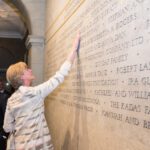 Someone touching a large wall with engraved names